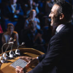 Side view of Caucasian businessman standing and giving presentation in the auditorium